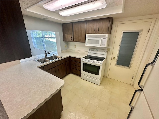 13102 Pembrook Ct, Hudson, FL 34667 - kitchen featuring white appliances, a raised ceiling, a peninsula, light countertops, and dark brown cabinetry