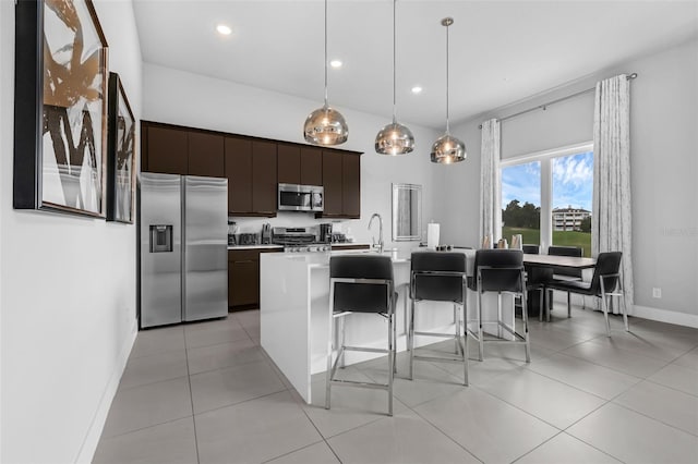7740 Sandy Ridge Dr Unit 235, Reunion, FL 34747 - kitchen featuring appliances with stainless steel finishes, a breakfast bar area, light countertops, dark brown cabinetry, and a kitchen island with sink