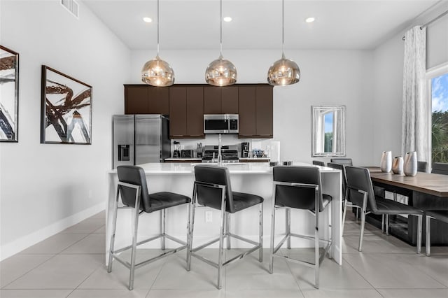 7740 Sandy Ridge Dr Unit 235, Reunion, FL 34747 - kitchen featuring appliances with stainless steel finishes, light countertops, a breakfast bar, a kitchen island with sink, and dark brown cabinets