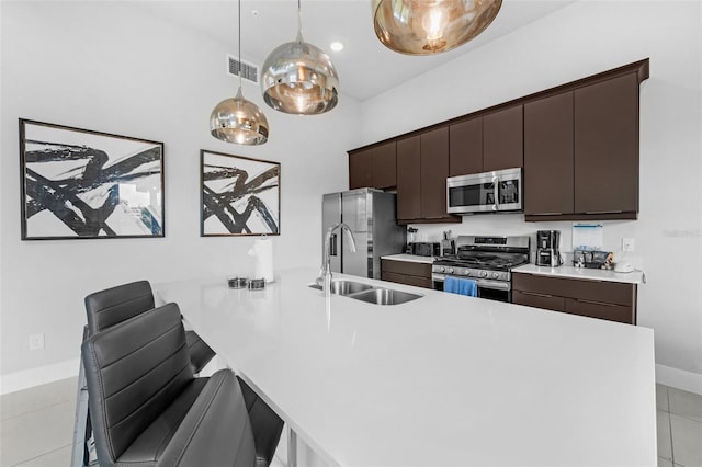 7740 Sandy Ridge Dr Unit 235, Reunion, FL 34747 - kitchen with stainless steel appliances, light countertops, a peninsula, dark brown cabinets, and pendant lighting