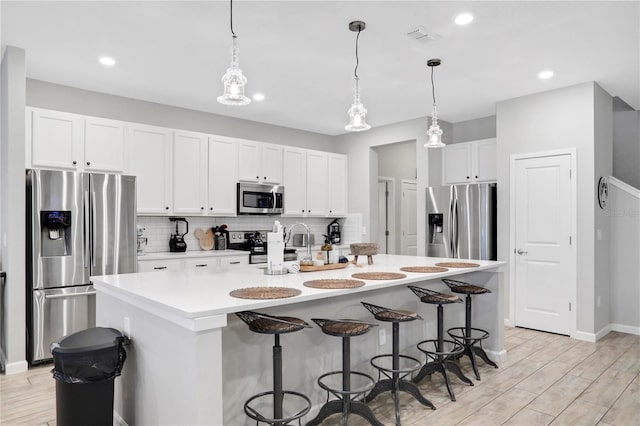 2541 Shanti Dr, Kissimmee, FL 34746 - kitchen featuring stainless steel appliances, decorative backsplash, white cabinets, a breakfast bar area, and recessed lighting