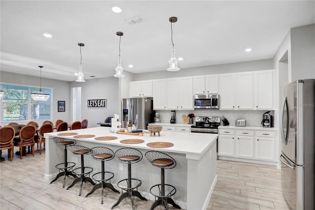 2541 Shanti Dr, Kissimmee, FL 34746 - kitchen featuring appliances with stainless steel finishes, a breakfast bar, decorative backsplash, light wood finished floors, and recessed lighting
