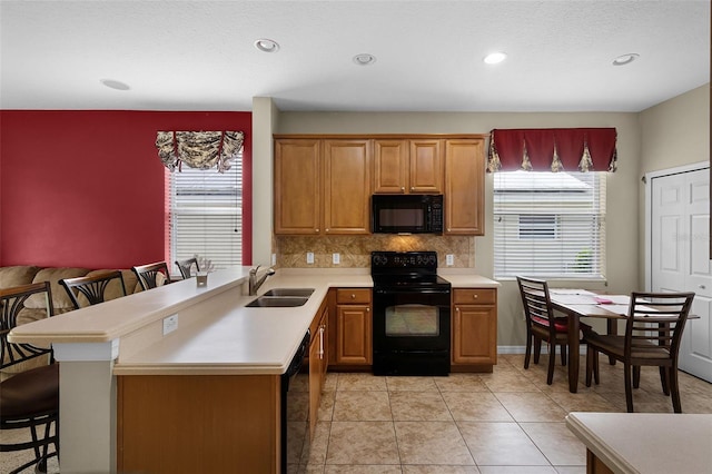 123 Preston Ave, Davenport, FL 33837 - kitchen featuring black appliances, a breakfast bar, light countertops, healthy amount of natural light, and recessed lighting