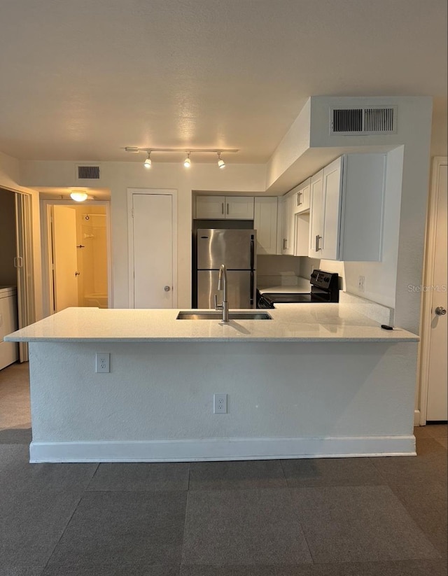 7280 Westpointe Blvd Unit 823, Orlando, FL 32835 - kitchen with freestanding refrigerator, black / electric stove, a peninsula, washer / dryer, and rail lighting