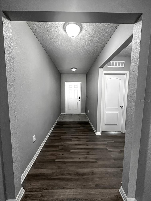 388 Rooks Loop, Haines City, FL 33844 - doorway to outside with a textured ceiling, dark wood-type flooring, and a textured wall