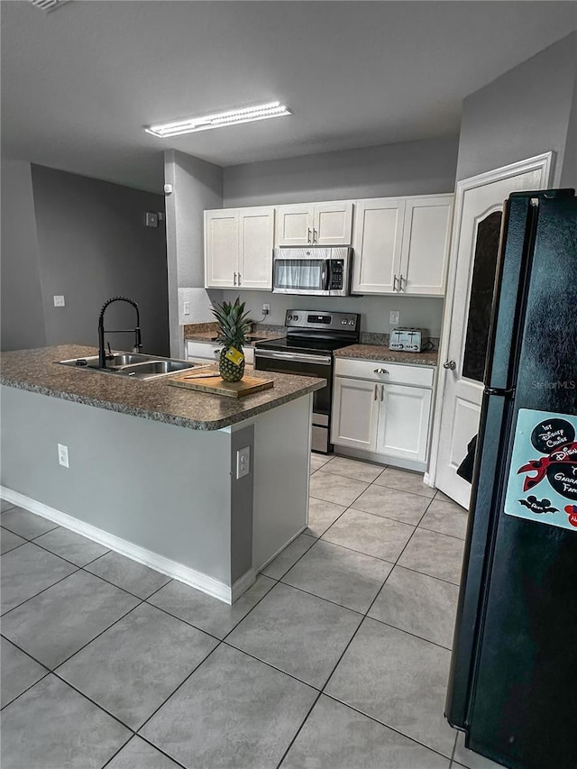 388 Rooks Loop, Haines City, FL 33844 - kitchen with stainless steel appliances, white cabinets, light tile patterned flooring, and a center island with sink