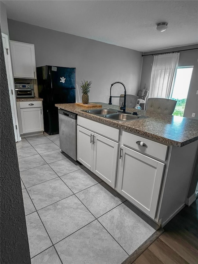 388 Rooks Loop, Haines City, FL 33844 - kitchen with white cabinets, stainless steel dishwasher, dark countertops, and freestanding refrigerator
