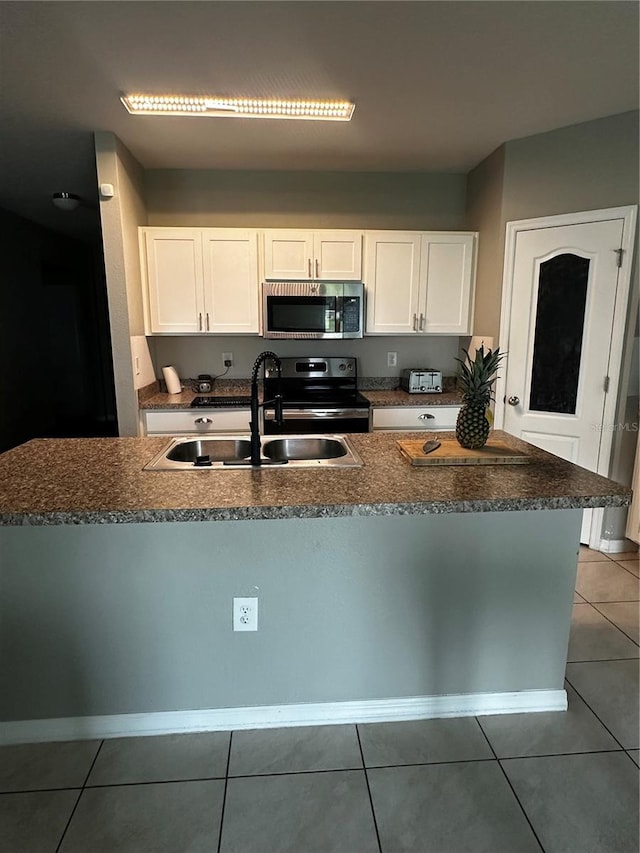 388 Rooks Loop, Haines City, FL 33844 - kitchen with appliances with stainless steel finishes, light tile patterned floors, white cabinets, and dark stone countertops