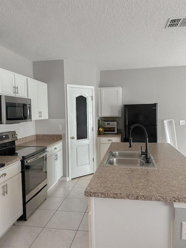 388 Rooks Loop, Haines City, FL 33844 - kitchen with stainless steel appliances, white cabinetry, an island with sink, light tile patterned flooring, and a textured ceiling