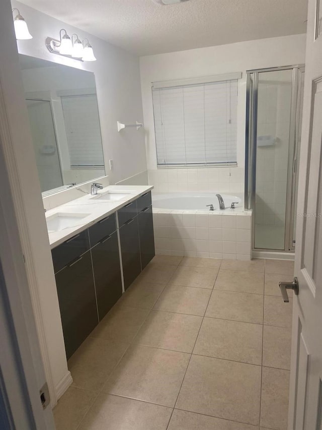 2618 San Simeon Way, Kissimmee, FL 34741 - full bathroom with tile patterned floors, double vanity, a bath, a shower stall, and a textured ceiling
