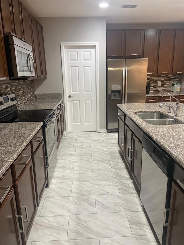 2618 San Simeon Way, Kissimmee, FL 34741 - kitchen featuring appliances with stainless steel finishes, light marble finish floors, decorative backsplash, dark brown cabinetry, and recessed lighting