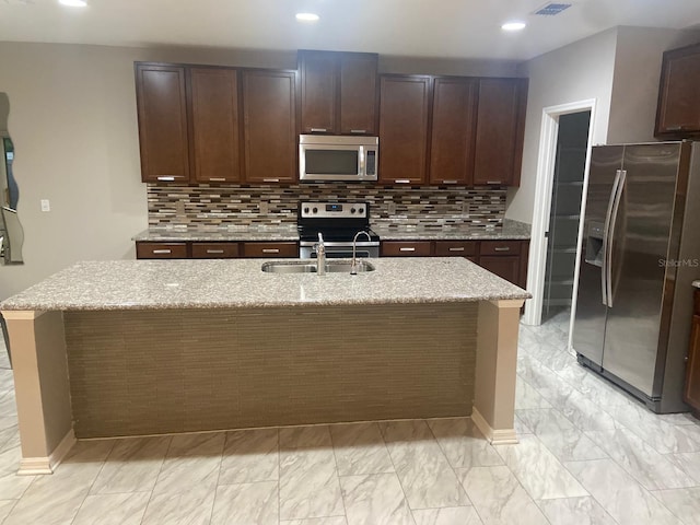 2618 San Simeon Way, Kissimmee, FL 34741 - kitchen featuring stainless steel appliances, light marble finish flooring, backsplash, a center island with sink, and light stone counters
