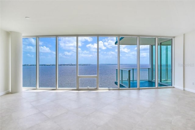 spare room featuring a wealth of natural light, a wall of windows, and a water view