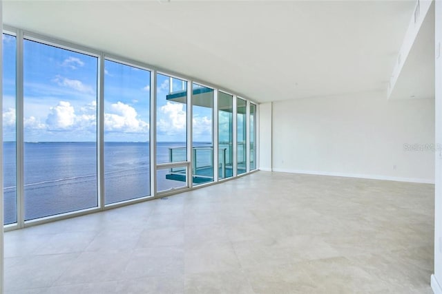 spare room featuring floor to ceiling windows and a water view