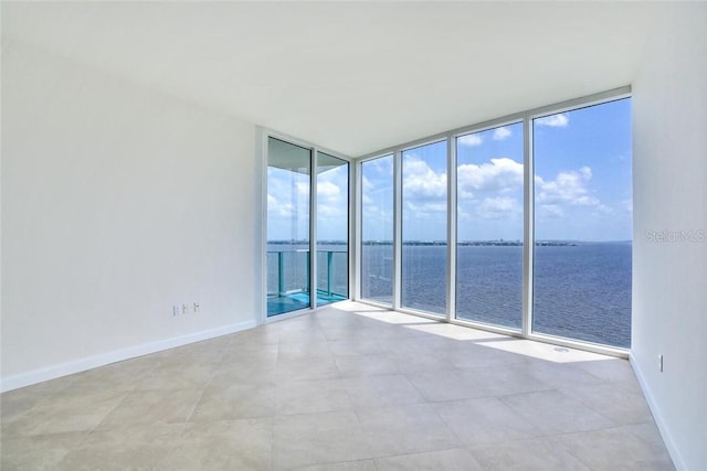 unfurnished room with a water view and a wall of windows