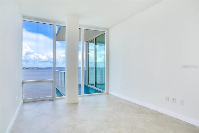 unfurnished room featuring a water view and expansive windows