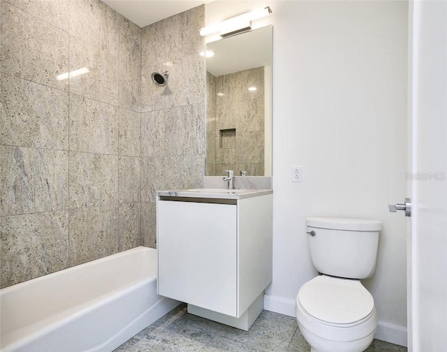 full bathroom featuring tile patterned flooring, toilet, tiled shower / bath combo, and vanity