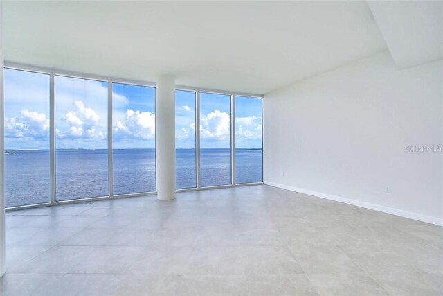 spare room with floor to ceiling windows and a water view