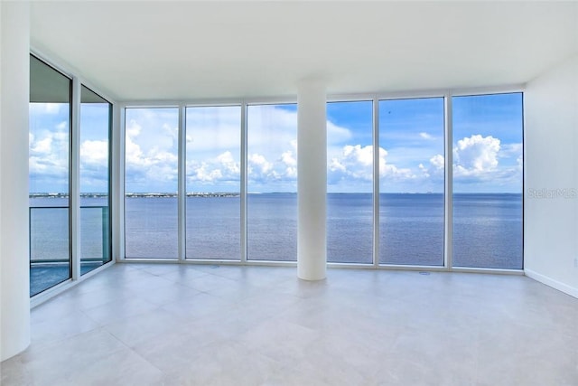 unfurnished room featuring a water view and a wall of windows