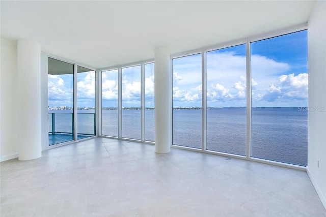 unfurnished room featuring a water view, a wall of windows, and a healthy amount of sunlight