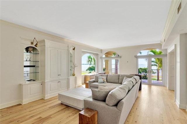 living room with light wood-type flooring, crown molding, french doors, and a wealth of natural light