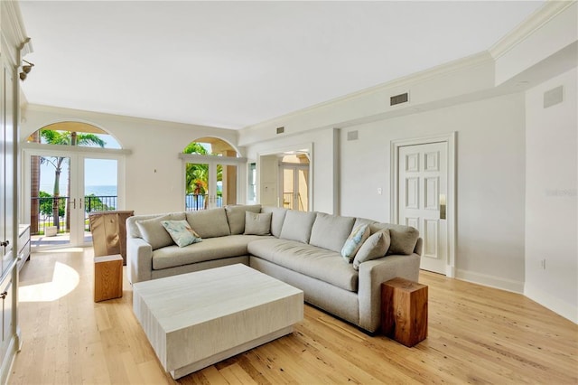 living room with light hardwood / wood-style floors, french doors, and ornamental molding