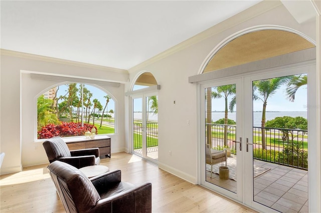 entryway with light wood-type flooring, crown molding, french doors, and a water view