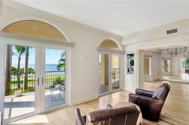 living room featuring french doors, a water view, a wealth of natural light, and light wood-type flooring