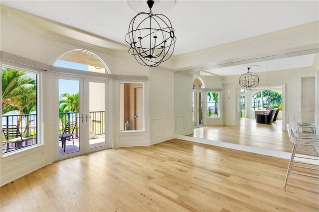 entryway with a notable chandelier, crown molding, light hardwood / wood-style floors, and french doors