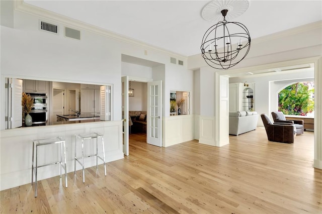 interior space with a notable chandelier, light hardwood / wood-style floors, and ornamental molding