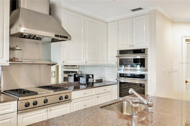 kitchen with wall chimney exhaust hood, stainless steel appliances, and white cabinets