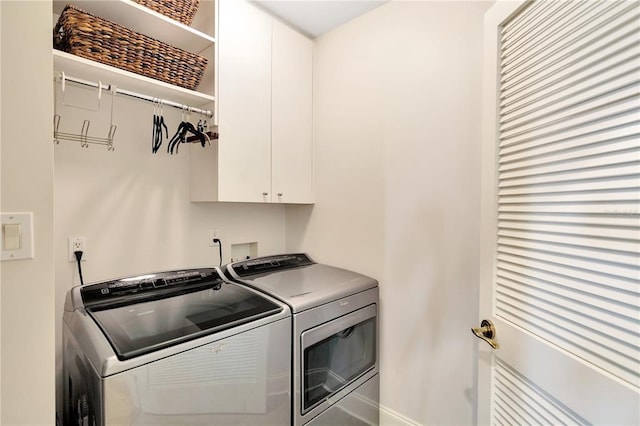 clothes washing area with washer and clothes dryer, cabinets, and washer hookup