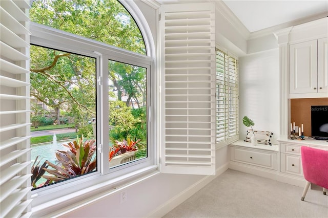 carpeted home office with built in desk and ornamental molding