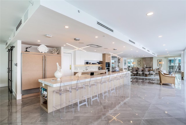 kitchen featuring white cabinetry, a kitchen bar, a large island, and a wealth of natural light