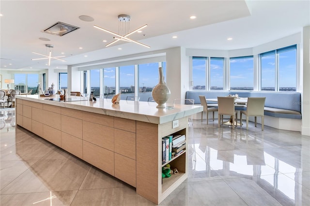 kitchen with a notable chandelier, black electric stovetop, a large island, and light brown cabinets