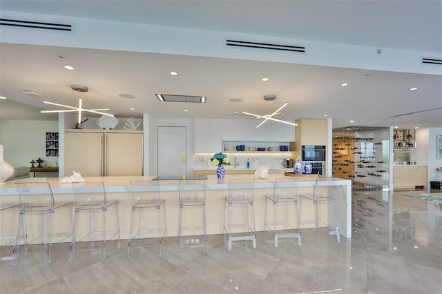 kitchen with pendant lighting, built in refrigerator, white cabinets, and a kitchen bar