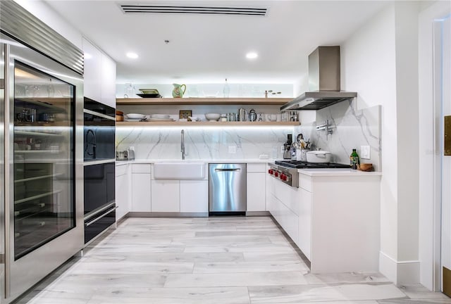 kitchen with white cabinetry, island exhaust hood, stainless steel appliances, and sink