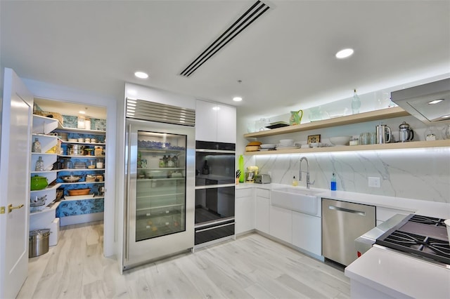 kitchen featuring stainless steel dishwasher, light hardwood / wood-style floors, sink, and white cabinets