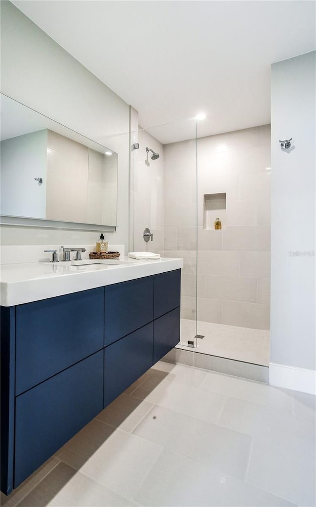 bathroom featuring a tile shower, vanity, and tile patterned flooring