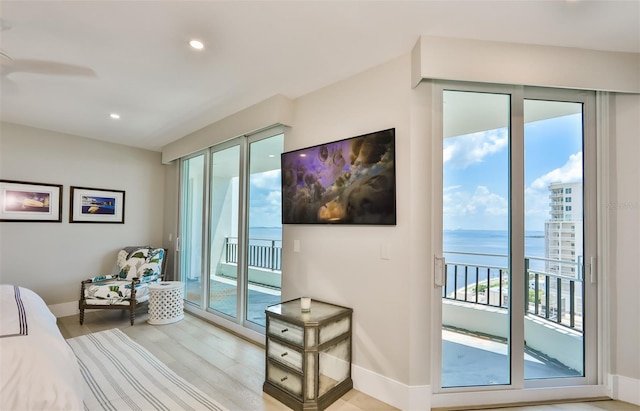 bedroom with a water view, access to outside, and light wood-type flooring