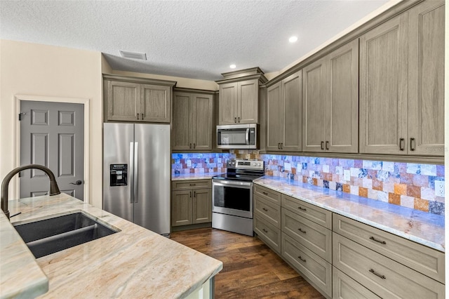 kitchen with stainless steel appliances, dark wood-type flooring, a textured ceiling, sink, and backsplash