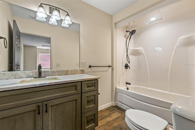 full bathroom featuring wood-type flooring, toilet, a textured ceiling, vanity, and bathtub / shower combination