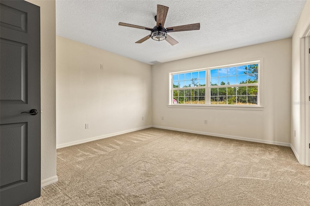 spare room with a textured ceiling, light colored carpet, and ceiling fan