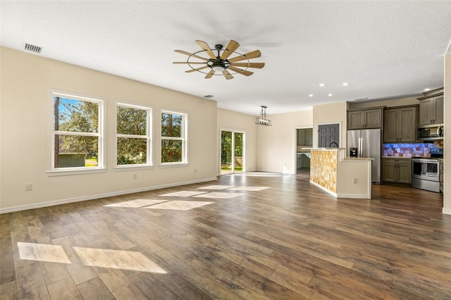 unfurnished living room with a wealth of natural light, dark hardwood / wood-style floors, and ceiling fan