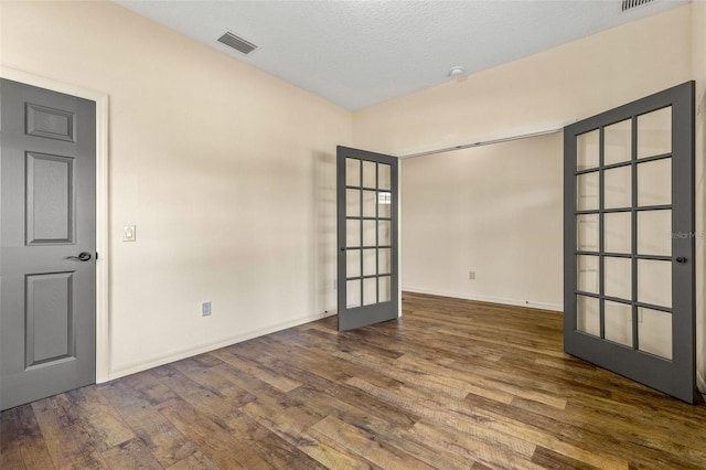 unfurnished room with dark hardwood / wood-style flooring, a textured ceiling, and french doors