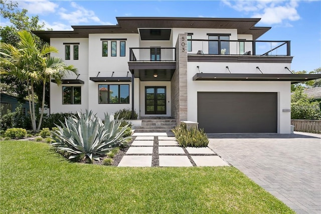 view of front facade with a front yard, french doors, a balcony, and a garage