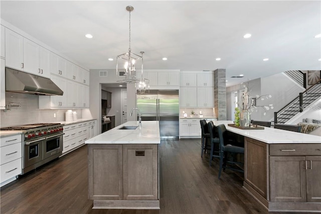 kitchen with a large island with sink, white cabinetry, sink, and premium appliances