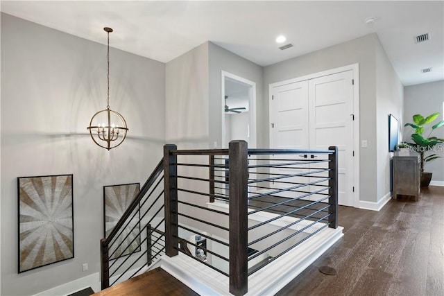 staircase with hardwood / wood-style floors and a chandelier