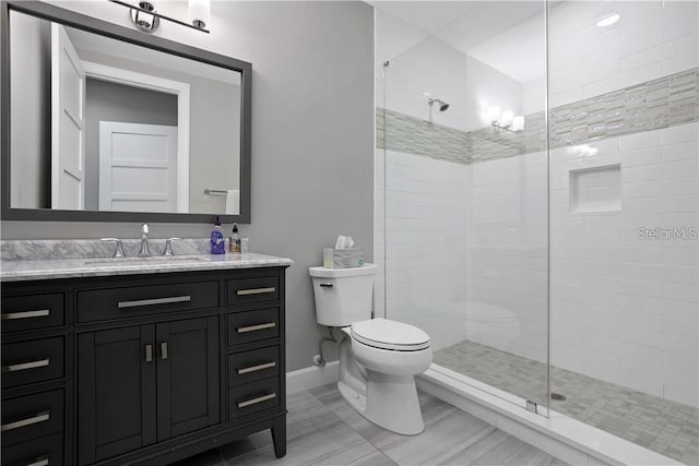 bathroom with toilet, vanity, and tiled shower