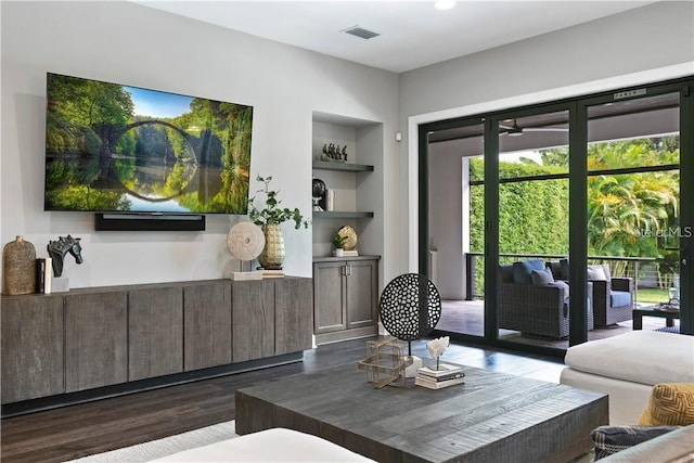 living room with built in shelves and dark hardwood / wood-style flooring